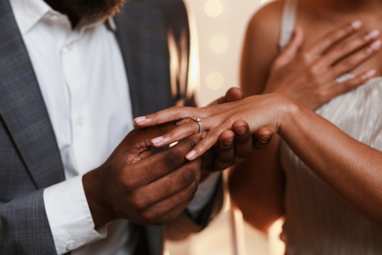 a close-up image of a bride and groom holding hands